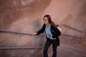 Young woman standing and the stairs of the underpass, holding her stomach